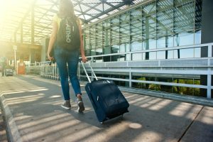 A woman walking on a pathway with her luggage and backpack.