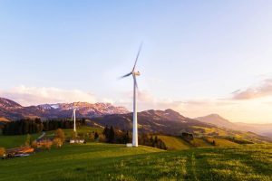 Two white windmills on top of a natural clearing.