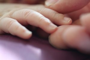A close-up shot of two hands reaching to hold each other.