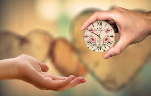 A person handing a miniature clock to another person.