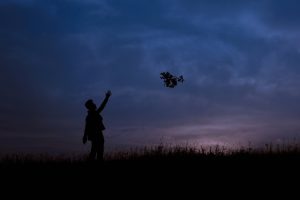 A man letting go of a bundle of flowers during sunset.