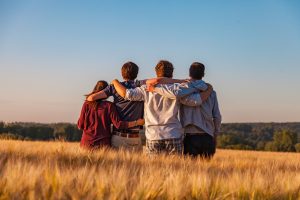 Four young adults huddle together while facing away from the camera.