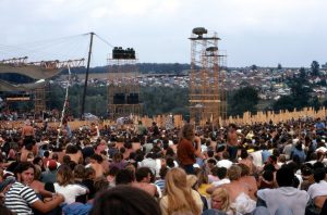 Joe Cocker performs on stage in front of a crowd at the Woodstock Music and Art Fair.