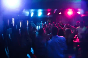 People dancing inside a building with blue and pink lights.