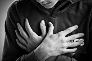 A person holding their hands over their chest.