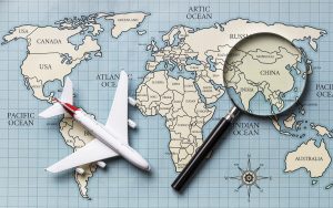 A miniature airplane and a magnifying glass on a world map.
