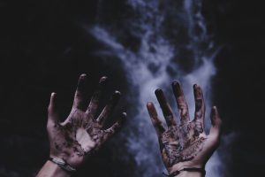 A person with black liquids on their hands.