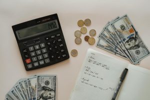 A black calculator beside coins and a notebook.