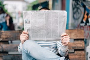 A man sitting on a bench reading a newspaper.