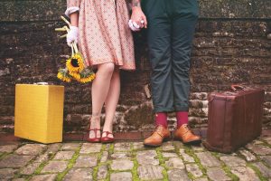 A couple holding hands with briefcases next to them.