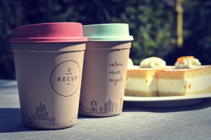 Two reusable cups beside a plate of sponge cakes.