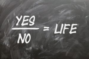 A chalkboard that reads yes split with a no, equaling life.