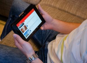 Person holding tablet showing videos.