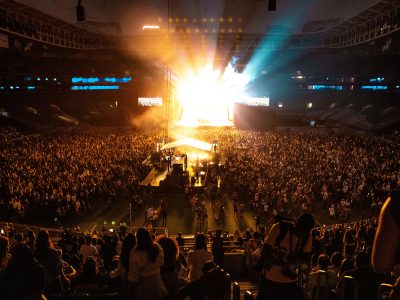 Lively full stadium concert with bright light coming from the stage.