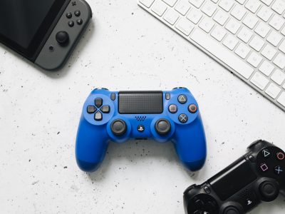 Top view of various gaming controllers and a keyboard on a white surface.