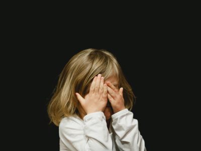 Little girl covering face with hands out of fear