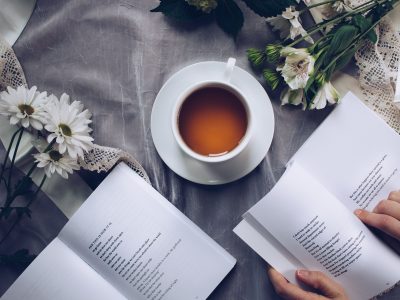 Inviting cozy reading setup with tea, poetry books, and fresh flowers on a table.