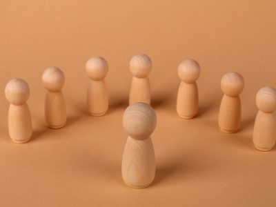 Minimalist scene of wooden peg dolls arranged in a circle on a brown surface.