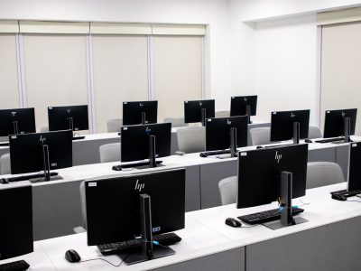 Spacious and minimalist computer lab with rows of black monitors.