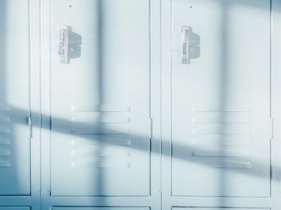 A row of bright blue school lockers illuminated by natural sunlight, casting shadows.