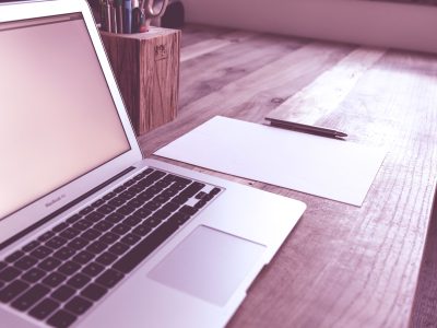 A clean and organized desk with a laptop, paper, and pen, ideal for productivity.