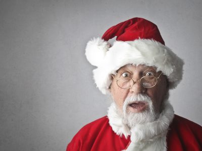 A surprised Santa Claus in traditional red outfit and glasses, expressing joy and wonder.