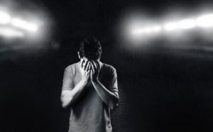 black and white photo of a man with his hands covering his face
