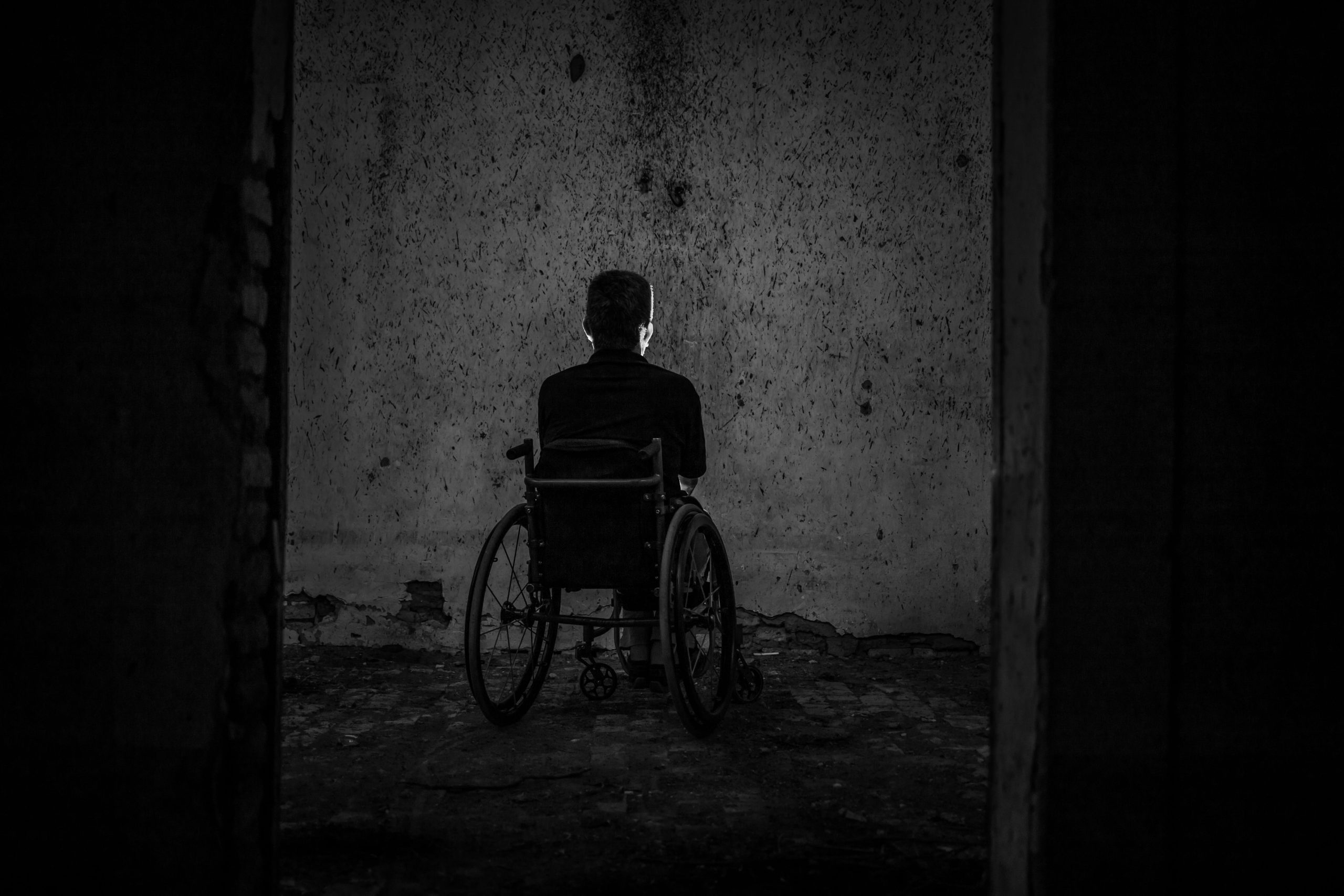 A silhouette of a wheelchair user in dark lighting.