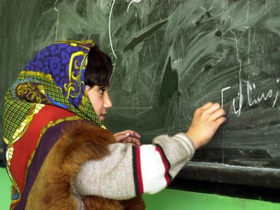 Young Afghan girl writes on a chalkboard
