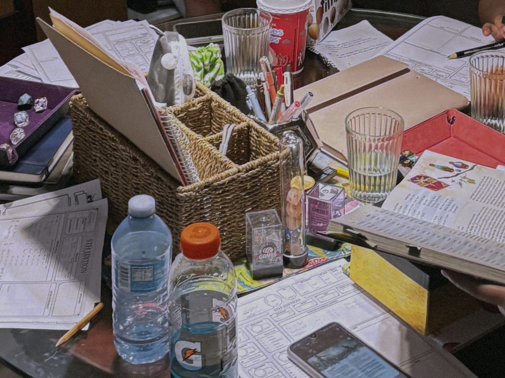 Photo of a table covered in paper, pens and cups during a character creation session.