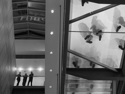 Silhouettes of people standing above on a glass-floor mezzanine