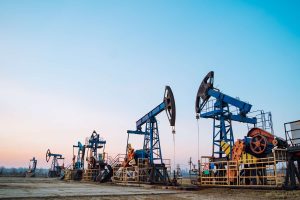 Several oil drilling machines working during the sunset. 