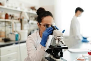 Woman in a lab looking through a microscope.
