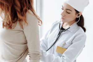 Photo of a female doctor examining a patient with a stethoscope.