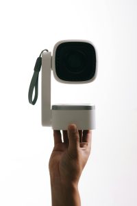 handheld-camera-projector A hand holding a white projector.