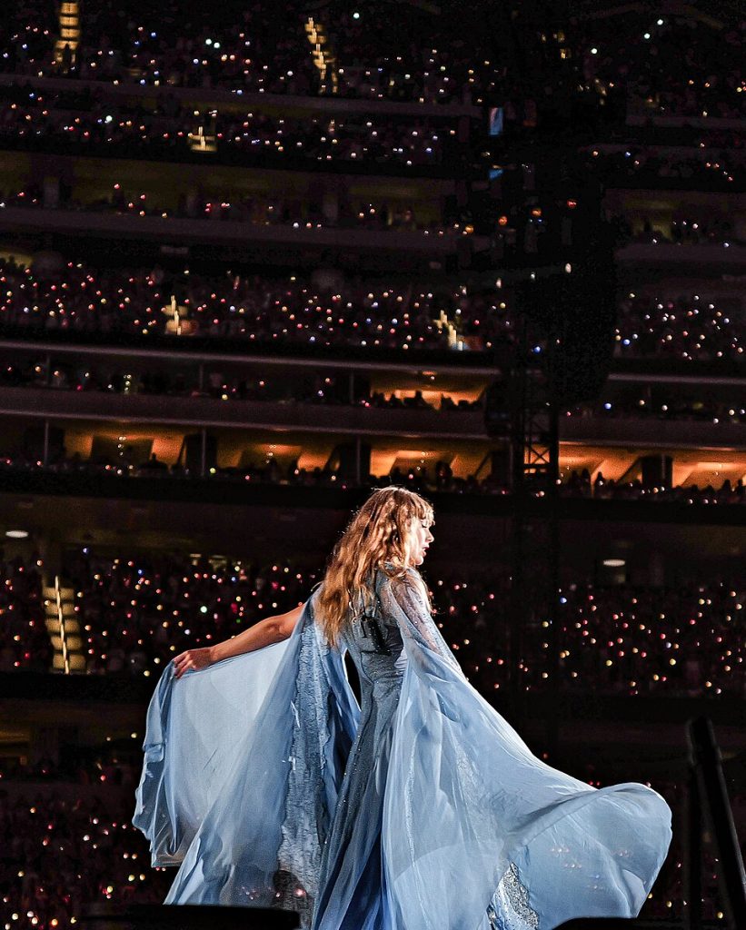 Photo of Taylor Swift on stage with a flowing blue dress.