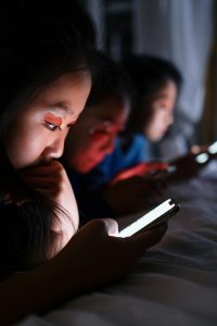 A group of kids staring at their own phones in silence.