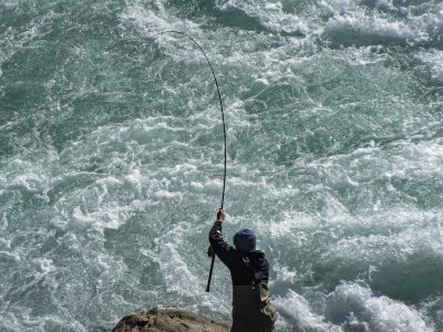 Person fishing from a rock in rapidly flowing water