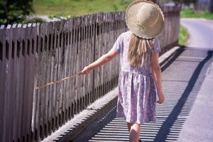 A girl in a sun hat walking on a road.
