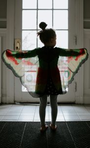 Little girl with cloth butterfly wings on.