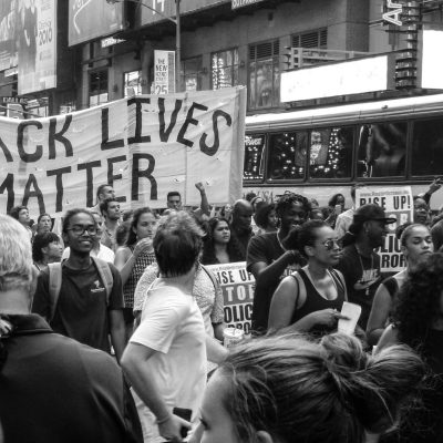 A black and white photo of a Black Lives Matter rally, featuring a large "Black Lives Matter" banner
