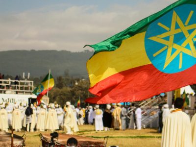Ethiopian flag waving on the right corner with men in white gathering around it.