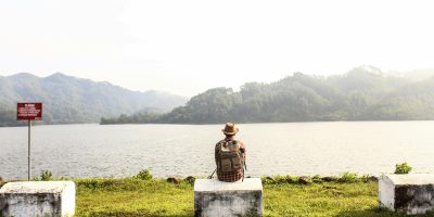 a man with a backpack sat by the lake