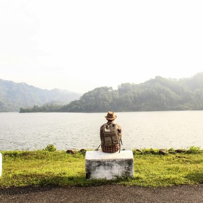 a man with a backpack sat by the lake