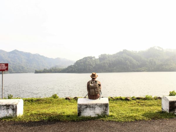 a man with a backpack sat by the lake