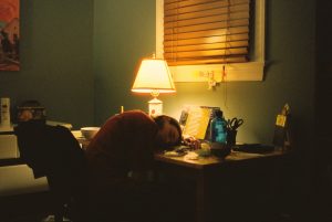 An overworked woman with her head on her desk.