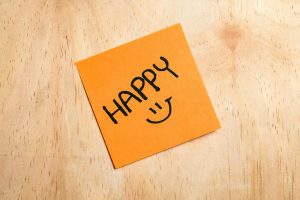 A yellow note on a wooden counter reading, "Happy."